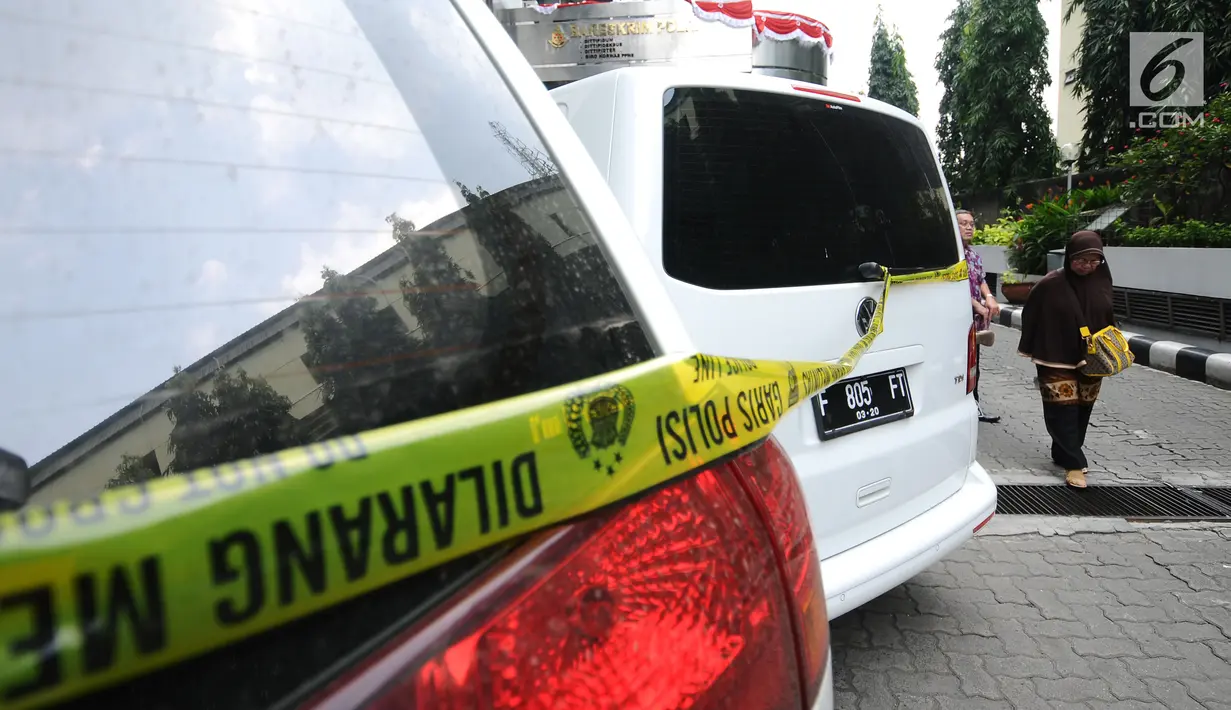 Warga melintas di belakang mobil milik tersangka kasus penipuan calon jamaah umroh yang disita Bareskrim Mabes Polri, Jakarta, Selasa (22/8). Hingga kini, polisi telah menetapkan tiga tersangka kasus tersebut. (Liputan6.com/Helmi Fithriansyah)