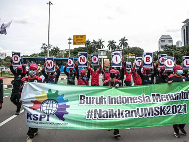 Massa aksi yang tergabung dalam Serikat Pekerja Indonesia (KSPI) membawa spanduk dan poster saat unjuk rasa di kawasan Patung Kuda, Jakarta, Rabu (16/12/2020). Dalam aksinya menyuarakan penolakan kaum buruh terhadap omnibus law UU Cipta Kerja. (Liputan6.com/Faizal Fanani)