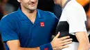 Petenis Swiss, Roger Federer berjabat tangan dengan Taylor Fritz dari AS pada akhir babak 32 besar Australia Terbuka di Melbourne, Jumat (18/1). Federer melaju mulus ke babak 16 besar setelah menang tiga set langsung 6-2 7-5 6-2. (DAVID GRAY/AFP)
