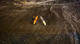 Dua peselancar bersiap menunggu ombak dari Samudra Pasifik saat akan berselancar di pantai La Pampilla, ibu kota Peru, Lima, 1 Maret 2017. Sekelompok peselancar hardcore memilih bermain selancar pada malam hari. (AP Photo/Rodrigo Abd)