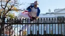 Seorang pria berselimut bendera Amerika Serikat tampak melompati pagar Gedung Putih di Washington, Kamis (26/11). Insiden itu terjadi pada saat Presiden AS Barack Obama sedang berada di dalam Gedung Putih merayakan hari Thanksgiving. (dailymail.co.uk)