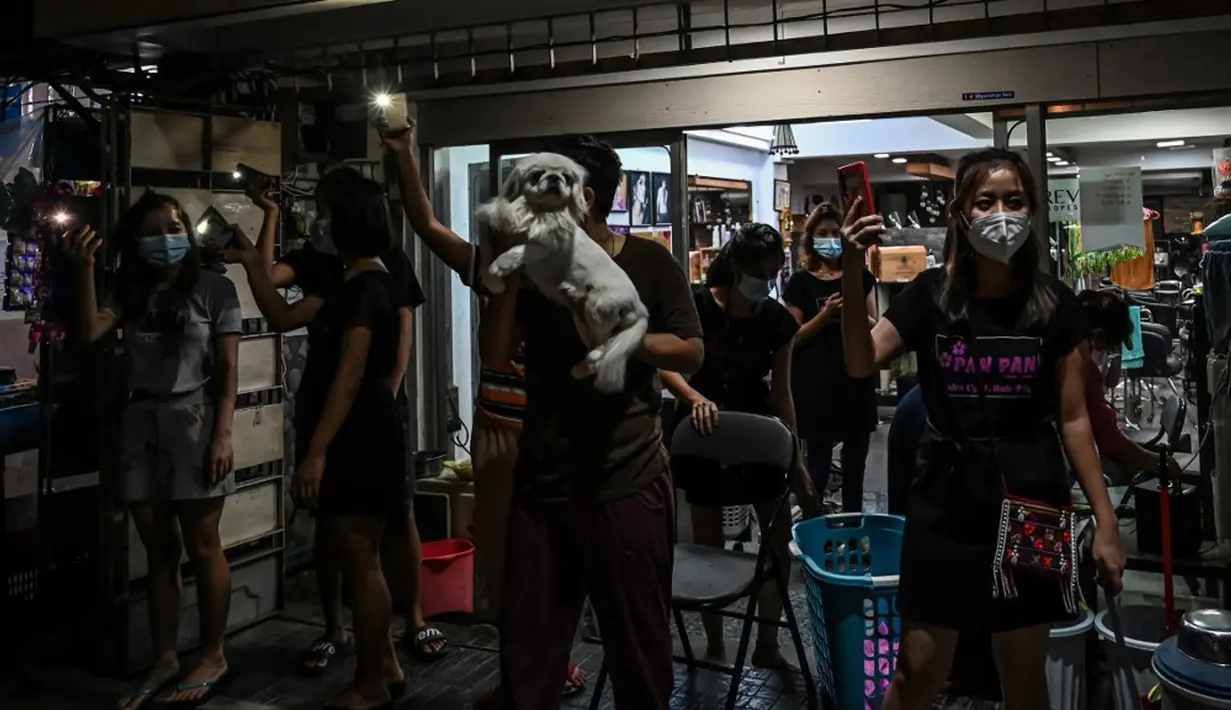 Orang-orang menyalakan ponsel mereka setelah seruan untuk protes keluar di media sosial di Yangon, Myanmar, 3 Februari 2021. Kudeta militer Myanmar terus memicu protes warga dengan membunyikan klakson mobil, menyalakan lampu ponsel, dan memukul-mukul panci. (STR/AFP)