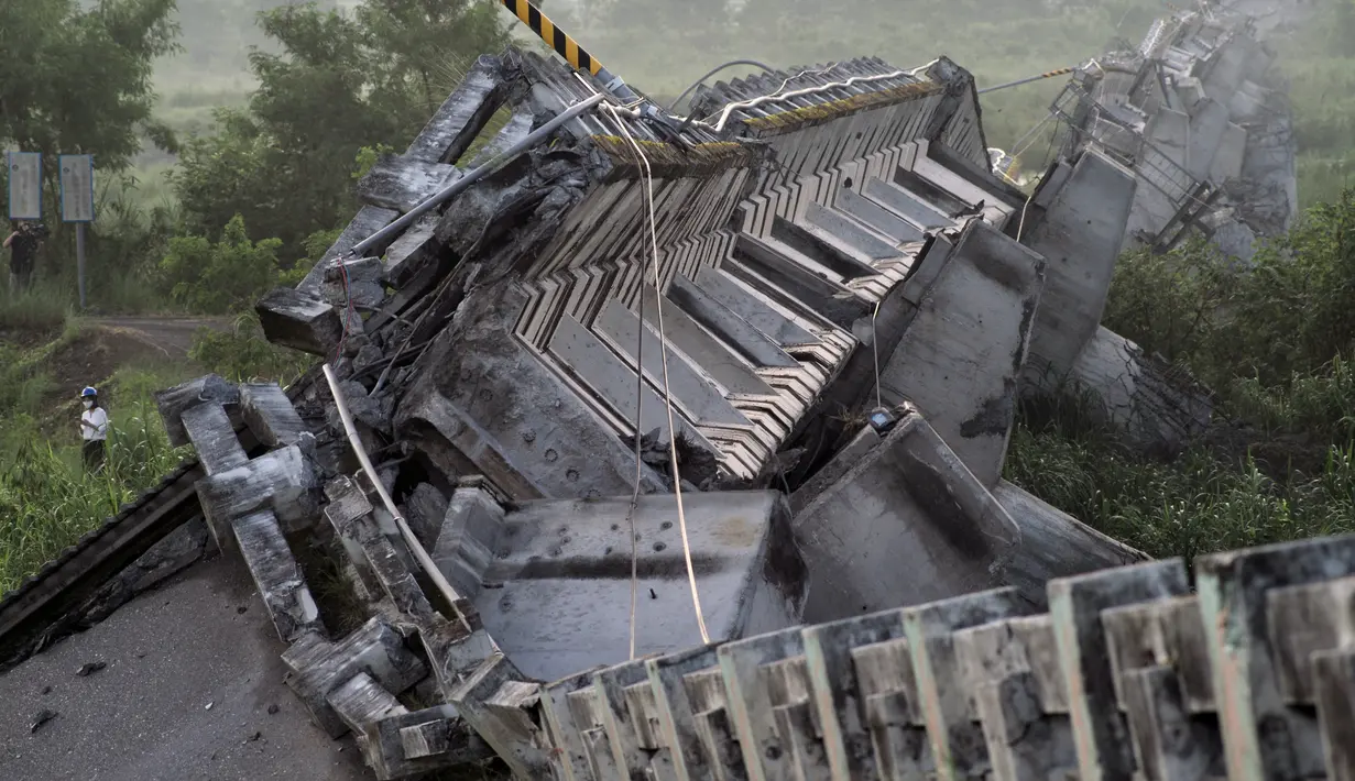 Seorang jurnalis (kiri) berjalan melewati jembatan Kaoliao yang runtuh di wilayah Hualien Taiwan timur (19/9/2022). Belum ada laporan korban jiwa akibat bencana alam tersebut. (AFP/Sam Yeh)