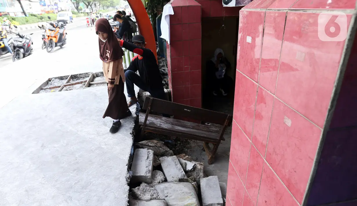 Seorang siswa berjalan keluar melintasi jalan darurat yang dibuat pihak sekolah di SDN Pondok Cina 1, Depok, Jawa Barat, Rabu (9/11/2022). Pembangunan trotoar Jalan Margonda Raya yang tidak membuat jalan darurat untuk siswa tersebut menghalangi pintu masuk SDN Pondok Cina 1 serta membahayakan siswa. (Liputan6.com/Herman Zakharia)