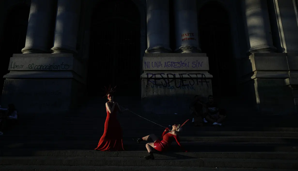 Seniman visual Hillvana Troncoso (kiri) dan Janis Duamante tampil di depan Perpustakaan Nasional saat pawai memperingati Hari Anti Kekerasan Terhadap Perempuan di Santiago, Chile, 25 November 2021. (AP Photo/Esteban Felix)