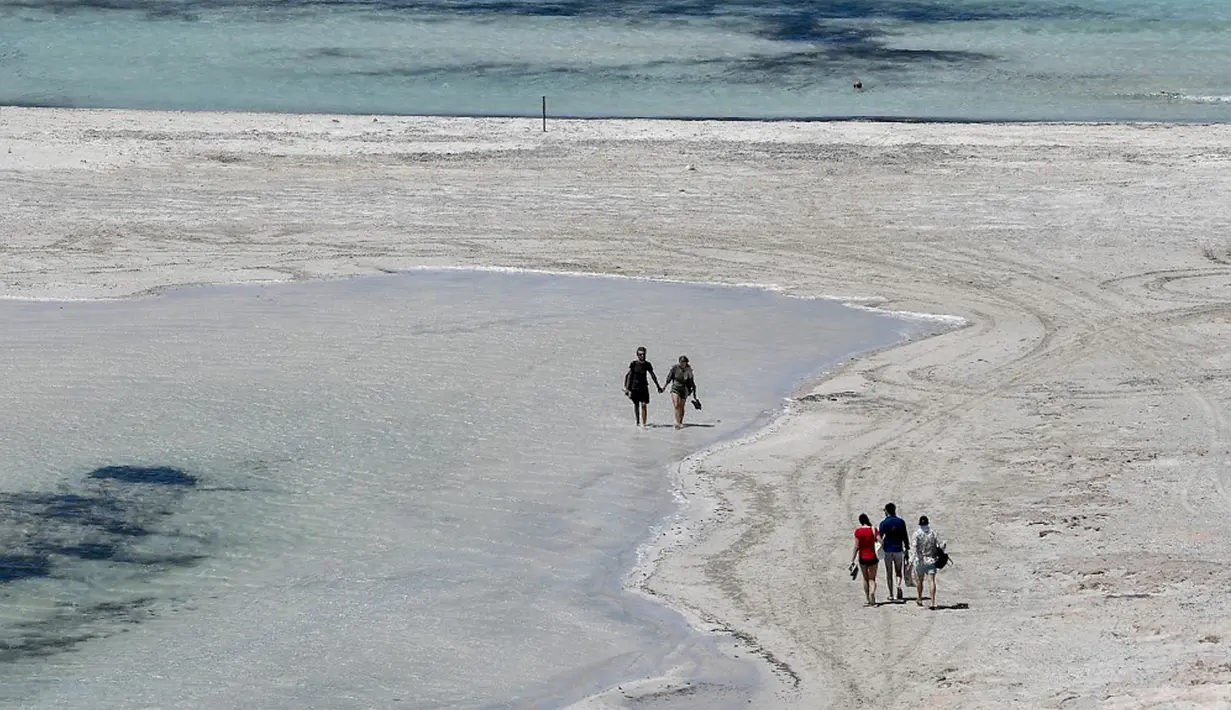 Turis berjalan di Pantai Balos dan laguna di barat laut Pulau Kreta, Yunani, Kamis (13/5/2021). Yunani mempermudah langkah-langkah terkait COVID-19 dalam menyambut turis internasional pada 14 Mei. (Louisa GOULIAMAKI/AFP)