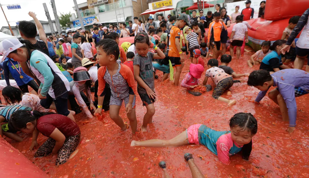 Sejumlah anak bermain di dalam kolam berisi tomat selama Festival Tomat di Hwacheon, Korea Selatan, 5 Agustus 2017. Di festival ini, pengunjung bebas memetik tomat yang siap dipanen, membuat saus tomat, dan mandi tomat. (AP Photo/Ahn Young-joon)