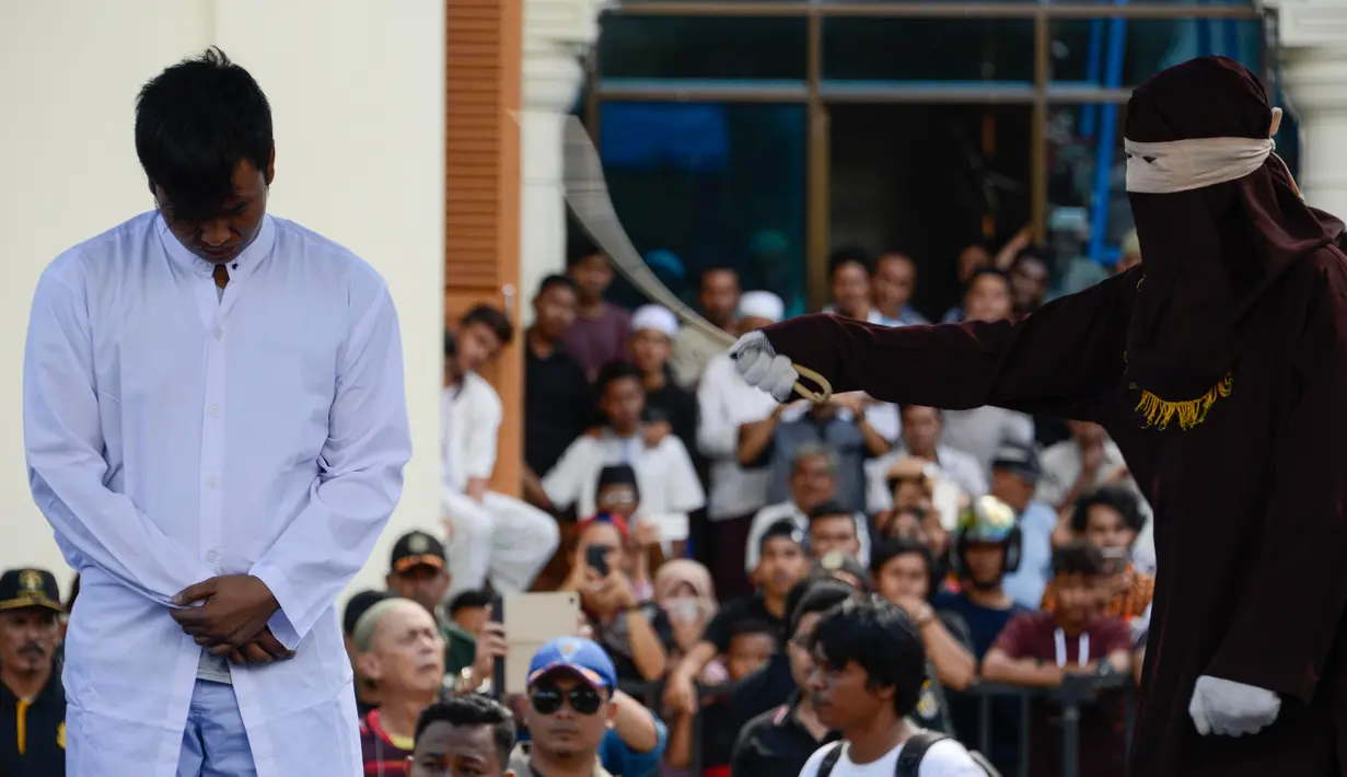 Salah satu dari dua pria terpidana kasus liwath alias gay saat dicambuk di depan Masjid Baiturrahim, Banda Aceh, (13/7). Mahkamah Syariah Kota Banda Aceh menjatuhi hukuman cambuk pasangan gay Nyakrab Bumin dan Muhammad Rustam. (AP Photo/Heri Juanda)