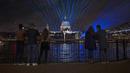 Lampu dan laser ditampilkan untuk menandai awal tahun 2022 setelah tengah malam di Jembatan Milenium yang melintasi Sungai Thames dan kubah Katedral St Paul di London, Inggris, Sabtu (1/1/2022). Pesta kembang api ditiadakan untuk tahun kedua berturut-turut karena COVID-19. (AP Photo/Matt Dunham)