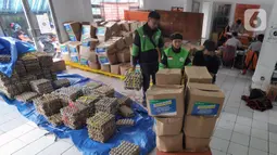 Pengemudi ojek online mengemas bansos untuk warga yang terdampak COVID-19 di Kantor Pos, Cibinong, Bogor, Jawa Barat, Senin (20/4/2020). Bansos khususnya disalurkan di zona merah persebaran yaitu Bogor, Depok, dan Bekasi dengan memberdayakan ojek online. (merdeka.com/Arie Basuki)