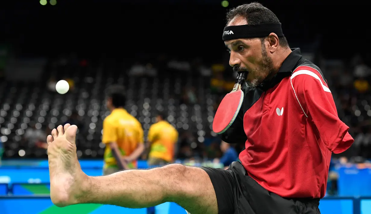 Penampilan atlet Mesir, Ibrahim Hamadtou saat bersiap melempar bola dengan bantuan kakinya ke arah lawannya, atlet Jerman Thoma Rau pada cabang tenis meja tunggal putra di ajang Paralimpiade 2016, Rio de Janeiro, 9 September 2016. (CHRISTOPHE SIMON/AFP)