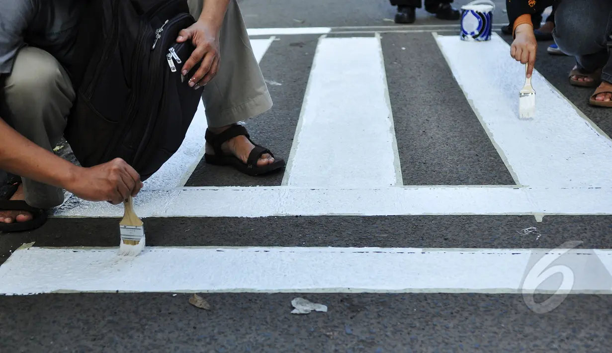 Suasana pengecatan jalur zebra cross di depan Stasiun Sudirman, Jakarta, Jumat (13/3/2015). (Liputan6.com/Faizal Fanani)
