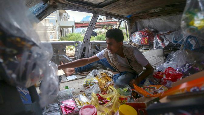 Majd al-Din al-Shamiri (16) menunggu pembeli di toko darurat di kawasan Jabal Sabr, Yaman pada 28 September 2019. Majd al-Din al-Shamiri mengubah mobil keluarganya yang rusak parah, akibat perang yang melanda, menjadi toko darurat untuk membantu keluarganya mencari nafkah. (Ahmad AL-BASHA/AFP)