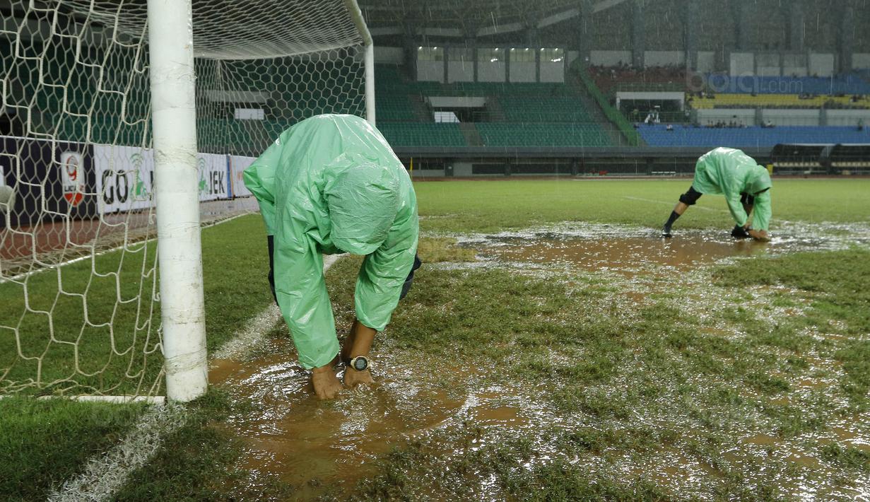 Para petugas berusaha menguras air yang menggenangi lapangan di Stadion Patriot, Bekasi, Senin (13/11/2017). Drainase yang buruk menyebabkan lapangan terendam air. (Bola.com/M Iqbal Ichsan)