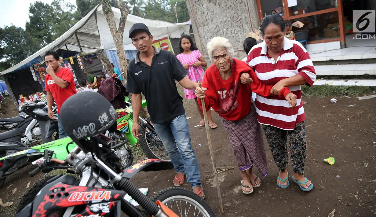 Keluarga pengungsi Gunung Agung membawa seorang wanita lanjut usia untuk memeriksa kesehatan di Posko Pengungsi Rendang, Bali, Sabtu (2/12). Keberadaan pos kesehatan tersebut dimanfaatkan warga untuk mengecek kesehatan. (Liputan6.com/Immanuel Antonius)