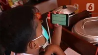 Seorang siswa sekolah dasar belajar dengan menggunakan wifi gratis yang disediakan oleh warkop Rizki, di Pondok Aren, Tangerang Selatan, Rabu (29/7/2020). Warung kopi tersebut menyediakan wifi gratis dan peminjaman laptop serta handphone. (Liputan6.com/Angga Yuniar)