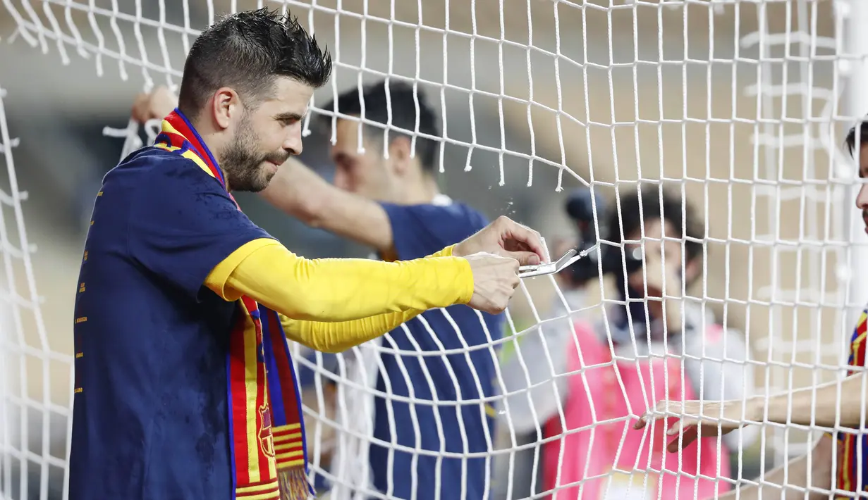 Bek Barcelona, Gerard Pique, melakukan selebrasi dengan menggunting jaring gawang usai menjuarai Copa del Rey di Stadion Olimpico de Sevilla, Minggu (18/4/2021). Barcelona menang 4-0 atas Athletic Bilbao. (AP Photo/Angel Fernandez)