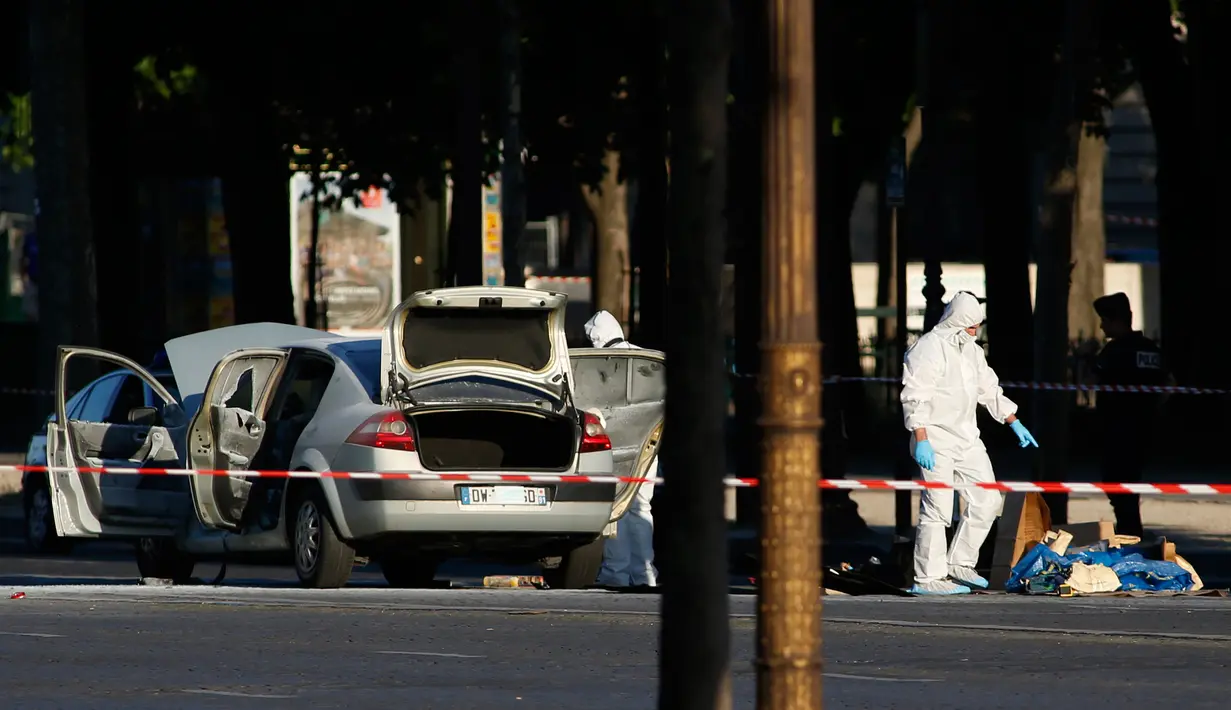Tim penyelidik forensik melakukan olah TKP lokasi serangan di kawasan Champs Elysees, Paris, Senin (19/6). Seorang pria yang diduga terkait dengan ekstrimis menabrakkan mobilnya ke arah mobil van polisi di jalanan ikonik itu. (AP Photo/Matthieu Alexandre)