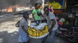 Pedagang memindahkan barang-barangnya saat protes menuntut pembebasan orang-orang yang diculik di Port-au-Prince, Haiti, 25 November 2021. Haiti mengalami peningkatan kasus penculikan terkait geng dan banyak yang menuntut uang tebusan. (AP Photo/Odelyn Joseph)