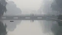 Pejalan kaki berjalan di sepanjang jalan dekat Gerbang India (tidak terlihat) di tengah kabut asap tebal di New Delhi, Kamis (3/11/2022). Tingkat partikel paling berbahaya yaitu PM2.5 adalah 588 per meter kubik pada Kamis pagi, menurut pemantauan IQAir. Partikel PM2.5 sangat kecil sehingga dapat memasuki aliran darah. (Money SHARMA / AFP)