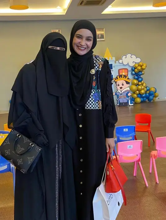 Shireen Sungkar juga hadir mengenakan dress hitam dengan motif di bunga di bagian atas. Serta kerudungnya. Sambil membawantas merahnya. [@_ummi_pipik_]