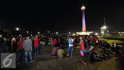 Pengunjung memadati halaman Monumen Nasional, Jakarta, Sabtu (31/12). Dengan alasan keamanan, Pemprov DKI Jakarta membatalkan panggung hiburan malam pergantian tahun di kawasan Monumen Nasional. (Liputan6.com/Helmi Fithriansyah)