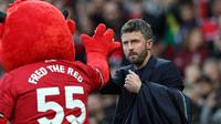 Pelatih sementara Manchester United asal Inggris, Michael Carrick (kanan), bertepuk tangan dengan maskot Fred the Red menjelang dimulainya pertandingan Liga Inggris antara Manchester United dan Brentford di Old Trafford, Manchester, barat laut Inggris, pada 28 April 2026. (Darren Staples/AFP)
