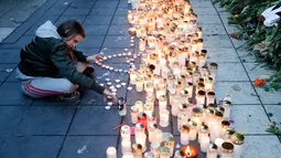 Seorang wanita menyalakan lilin di lokasi terjadinya serangan truk di Stockholm, Swedia, Minggu (9/4). Sebuah truk yang dibajak menabrakkan diri ke kerumunan pejalan kaki pada Sabtu (8/4) dan menewaskan empat orang. (AP Photo / Markus Schreiber)