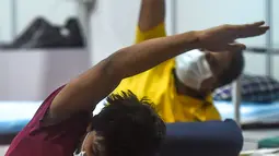Pasien melakukan yoga di dalam bangsal di kompleks olahraga Commonwealth Games (CWG) Village yang sementara diubah menjadi pusat perawatan Covid-19 di New Delhi, India, Kamis (16/7/2020). Kasus virus corona (Covid-19) di India hampir menyentuh angka 1 juta orang.  (Money SHARMA / AFP)