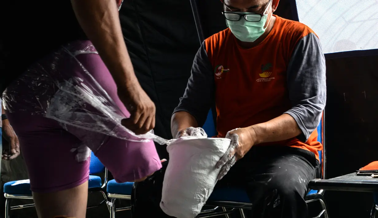 Petugas mengukur dan mencetak kaki palsu untuk seorang penyandang disabilitas di kantor Dinas Sosial Aceh, Senin (16/9/2019). Untuk tahun 2019 ini diberikan secara gratis sebanyak 100 kaki dan tangan palsu untuk para penyandang disabilitas di sejumlah kabupaten/kota. (CHAIDEER MAHYUDDIN / AFP)