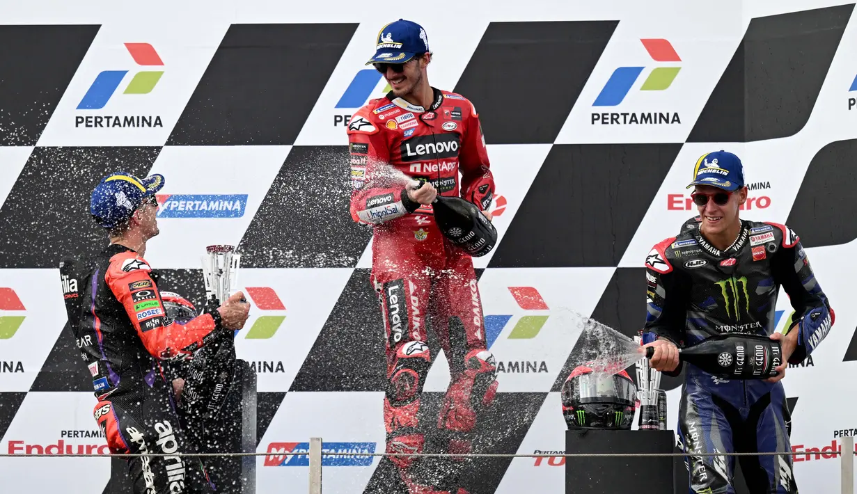 Pembalap Ducati Lenovo Team, Francesco Bagnaia (tengah), bersama pembalap Aprilia Racing, Maverick Vinales (kiri) dan pembalap Monster Energy Yamaha, Fabio Quartararo, melakukan selebrasi setelah menjadi juara di MotoGP Mandalika 2023, Minggu (15/10/2023) siang WIB. (AFP/Sonny Tumbelaka)