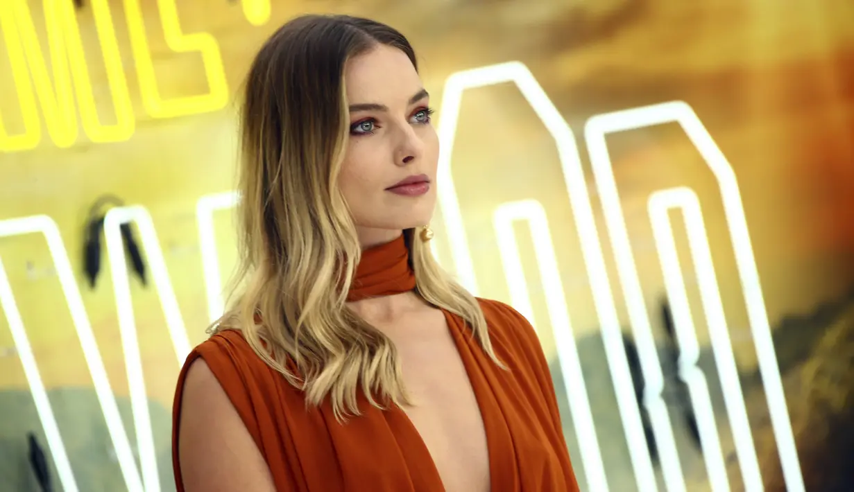 Aktris Margot Robbie berpose saat tiba menghadiri premier film Once Upon a Time In Hollywood di sebuah bioskop di London, Inggris (30/7/2019). Margot Robbie tampil seksi menggenakan gaun oranye tipis Oscar de la Renta untuk menyesuaikan musim panas di eropa. (AP Photo/Joel C Ryan)