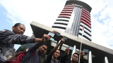 Aktivis Koalisi Masyarakat Sipil menunjukan Kartu Tanda Penduduk (KTP) Elektronik saat melakukan aksi di depan Gedung Komisi Pemberantasan Korupsi (KPK), Jakarta, Minggu (12/3). (Liputan6.com/Immanuel Antonius)