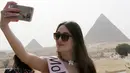 Cantiknya Kontestan Miss ECO Universe saat berselfie dengan latar belakang segitiga piramida di pinggiran Kairo, Mesir (10/4). Pemenang Miss Eco Universe 2016 akan memenangkan hadiah uang tunai USD 10.000. (REUTERS/Mohamed Abd El Ghany)