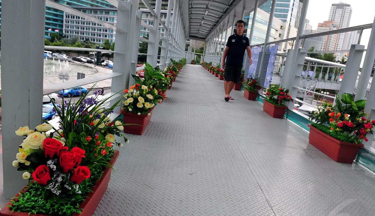 Pejalan kaki melintas di atas Jembatan Penyeberangan Orang (JPO) Bundaran HI yang dihias bunga, Jakarta. Foto diambil pada Rabu (3/12/2014). (Liputan6.com/Johan Tallo)