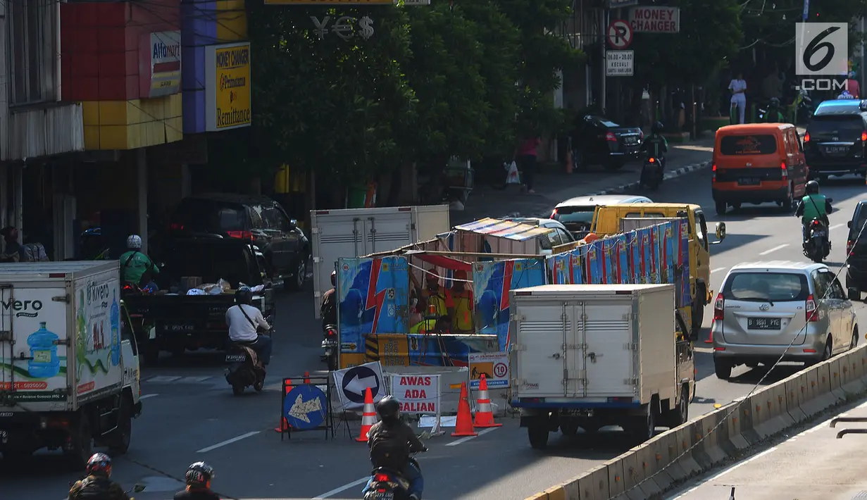 Pekerja beraktivitas di galian kabel yang berada di tengah jalan Gajah Mada, Jakarta, Sabtu (12/5). Galian kabel instalasi listrik bertegangan tinggi yang berada di tengah jalan ini membuat arus lalu lintas sedikit tersendat. (Merdeka.com/Imam Buhori)