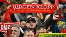 Seorang fans Liverpool membentangkan syal yang bertuliskan "Jurgen Klopp, kamu tak akan berjalan sendirian" saat laga putaran keempat Piala FA melawan Norwich City di Anfield, Liverpool, Inggris, Minggu (28/01/2024). (AFP/Paul Ellis)