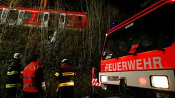 Petugas mengevakuasi rangkaian kereta komuter S-bahn yang tabrakan di Schaeftlarn di distrik Munich, Jerman pada 14 Februari 2022. Lebih dari 200 tim penyelamat dan polisi diterjunkan ke lokasi kecelakaan. (MICHAELA REHLE / AFP)