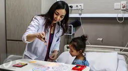 Seorang dokter membimbing pasien anak untuk mewarnai kertas bergambar telur Paskah di Rumah Sakit Siloam Simatupang, Jakarta, Minggu (27/3). Program "Stress Relief" ini membantu memulihkan pasien. (Liputan6.com/Fery Pradolo)