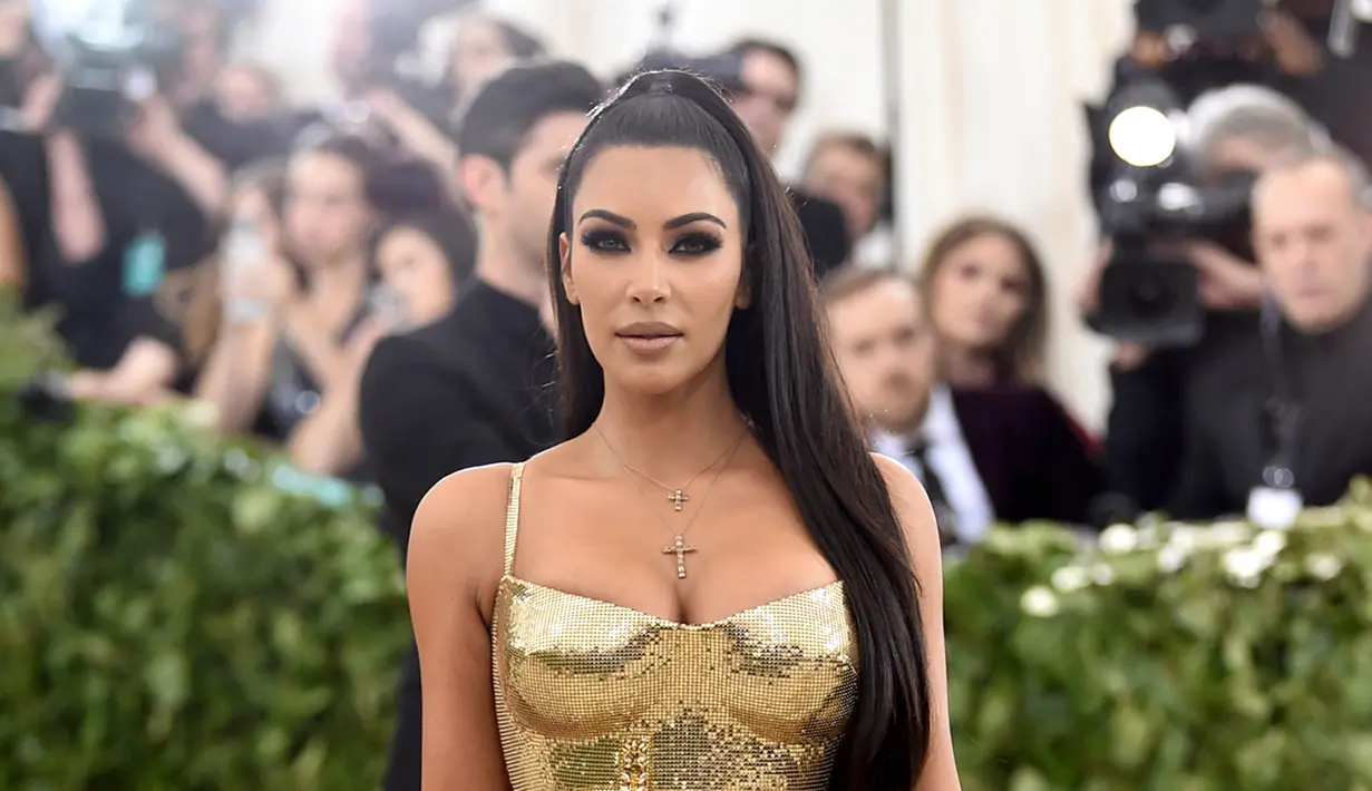 Aktris Kim Kardashian berpose saat menghadiri Met Gala 2018 di Metropolitan Museum of Art, New York (7/5). Kim Kardashian tampil seksi mengenakan gaun emas super ketat. (AP Photo/Evan Agostini)