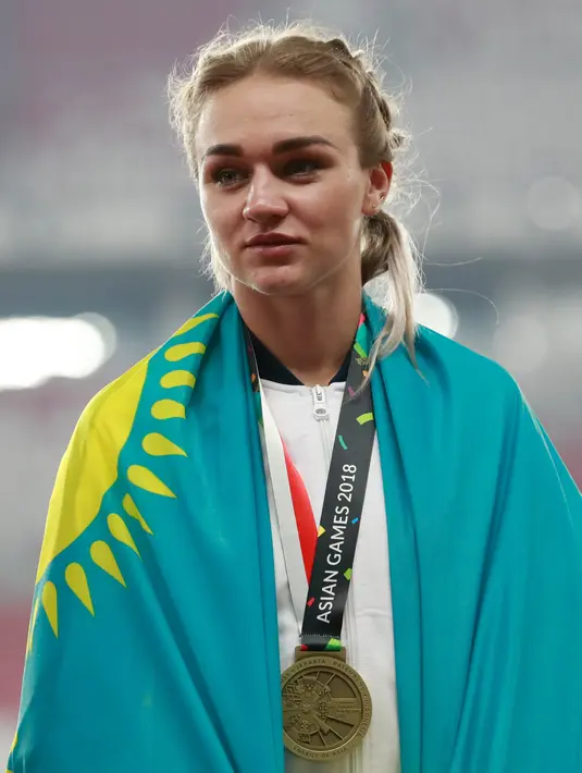 Atlet lari Kazakhstan, Elina Mikhina menggunakan medali perunggu usai finis di posisi ketiga untuk final 400m putri Asian Games 2018 di Jakarta, Minggu (26/8). (AP Photo/Bernat Armangue)