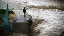 Seorang pria terlihat di sebelah sungai saat banjir melanda Ibu Kota Chile, Santiago, Minggu (17/4). Hujan lebat dan parah di Ibu Kota Chile selama akhir pekan lalu menyebabkan 1 orang tewas dan 7 orang masih dinyatakan hilang. (REUTERS/Ivan Alvarado)