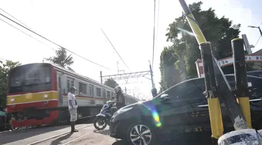 Kereta melintasi perlintasan kereta api di Jalan Duri Kosambi Raya, Jakarta, Rabu (15/1/2020). Warga setempat terpaksa membangun palang secara swadaya dan mengatur lalu lintas akibat perlintasan kereta di dekat Stasiun Rawa Buaya itu belum dipasang palang pintu otomatis. (merdeka.com/Iqbal Nugroho)