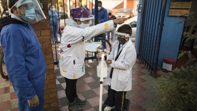 Seorang guru menunjukkan jalan kepada seorang siswa pada awal hari pertama kembali ke kelas tatap muka sejak Maret 2020 di Chia di pinggiran Bogota, Kolombia, Jumat (5/2/2021). Sejauh ini Kolombia melaporkan lebih dari 2,13 juta kasus Covid-19 dan lebih dari 55.100 kematian. (AP Photo/Ivan Valencia)