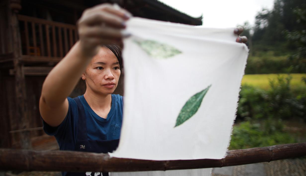 Seorang perempuan menjemur kain di sebuah bengkel kerja di Desa Etnis Dong Fengdeng di Wilayah Rongjiang, Provinsi Guizhou, China pada 6 September 2020. Warga setempat memanfaatkan kondisi cuaca musim gugur yang mendukung untuk membuat kain tradisional kelompok etnis Dong. (Xinhua/Liu Xu)