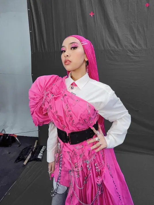 Jinan terlihat seperti penyanyi rock dengan layering yang unik. Ia padukan kemeja pink polos dengan kain pink sebagai aksen dan peniti seluruh bagian. Ia juga kenakan stocking hitam dengan hijab pink [@jinanlaetitia]
