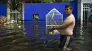 Seorang warga mengarungi jalan banjir membawa seekor burung dalam sangkar di Villahermosa, Meksiko, Rabu (11/11/2020). Banjir mengakibatkan hampir 10.000 orang ke tempat penampungan dan menewaskan sebanyak lima orang. (AP Photo/Felix Marquez)