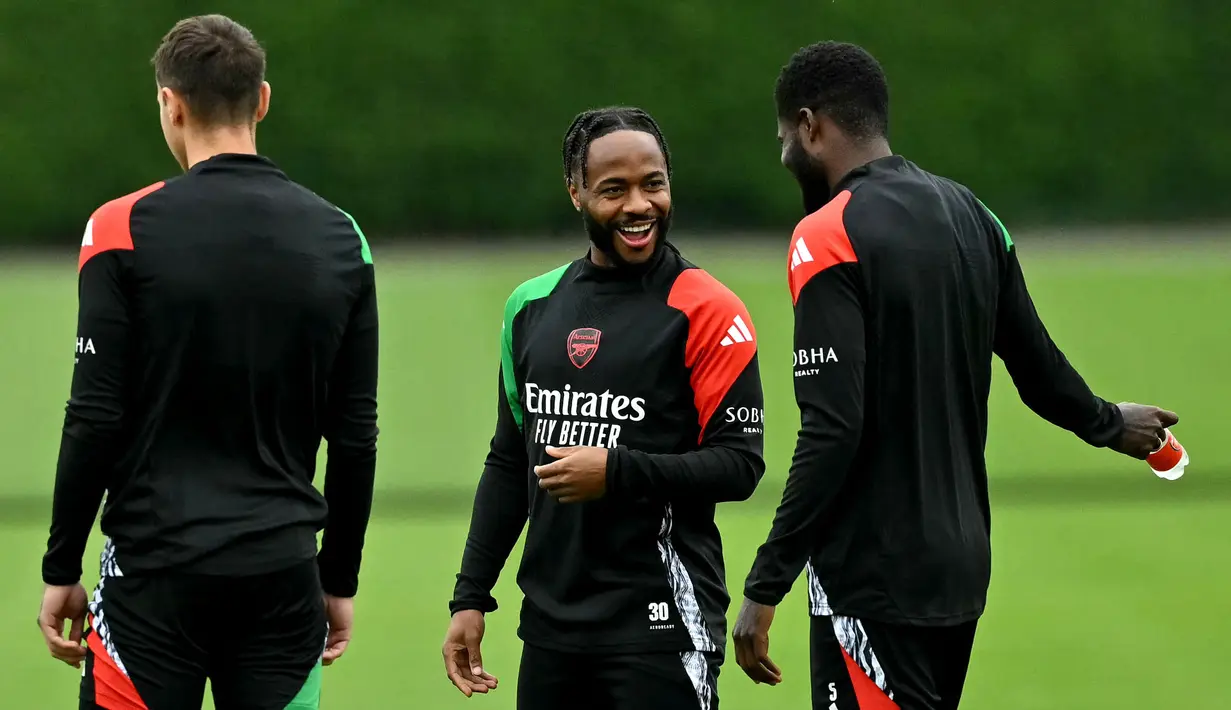 Pemain Arsenal, Raheem Sterling berbincang dengan rekan setimnya saat latihan menjelang laga lanjutan Liga Champions melawan PSG di Arsenal Training Centre, Hertfordshire, Inggris, Selasa (01/10/2024). (AFP/Glyn Kirk)