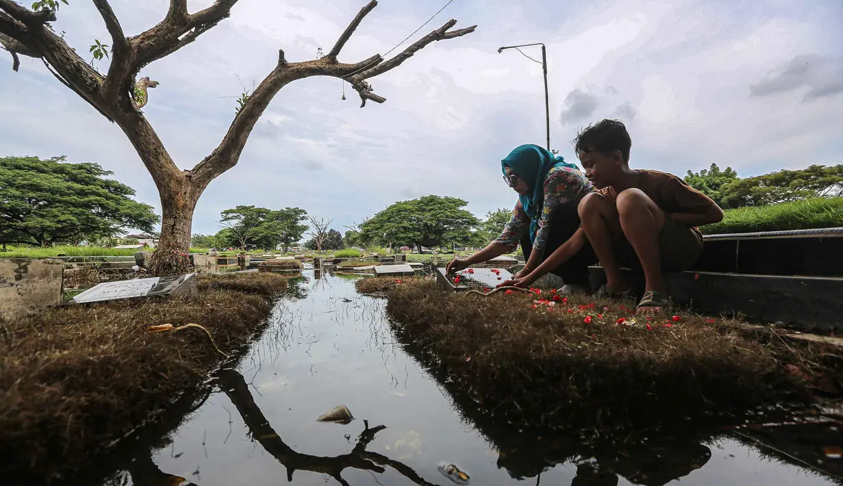 Diketahui, ziarah makam merupakan salah satu tradisi sebagian umat Islam yang dilakukan jelang memasuki bulan suci Ramadan. Tampak dalam foto, warga mengunjungi makam anggota keluarga mereka di Tempat Pemakaman Umum (TPU) Semper, Cilincing, Jakarta Utara pada 15 Februari 2026. (Syinatria RESPATI/AFP)