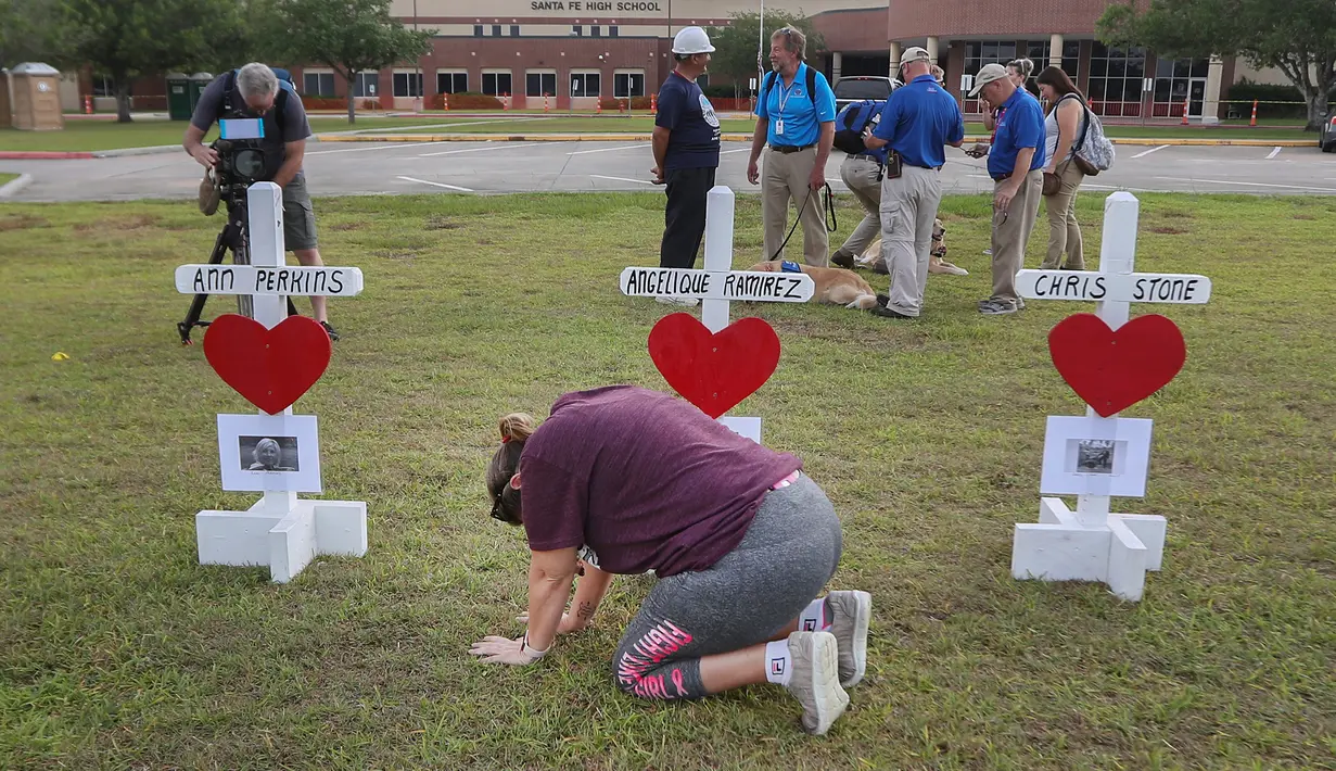 Penduduk Santa Fe, Lori Simmons menangis di depan salib saat acara mengheningkan cipta di depan SMA Santa Fe di Texas, AS, Senin (21/5). Pelaku penembakan Texas memakai senapan dan pistol untuk menembaki korban. (Steve Gonzales/Houston Chronicle via AP)